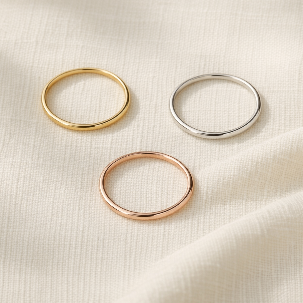 Tres anillos finos en oro amarillo, oro blanco y oro rosa sobre lino crema