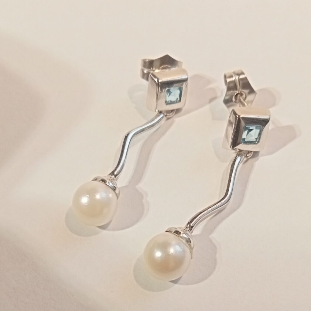 Pendientes de oro blanco con perlita colgante y detalle de aguamarina